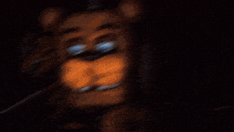 a close up of a brown teddy bear with blue eyes standing in the dark .