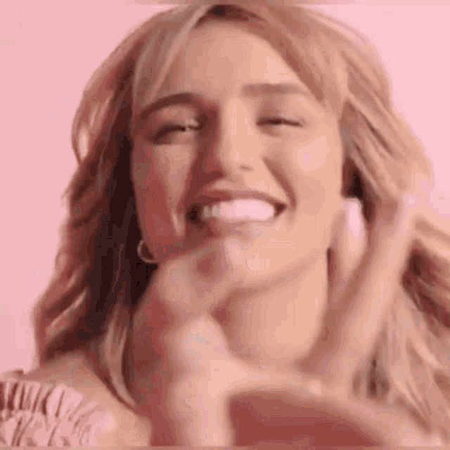 a close up of a woman making a peace sign with her hands and smiling .
