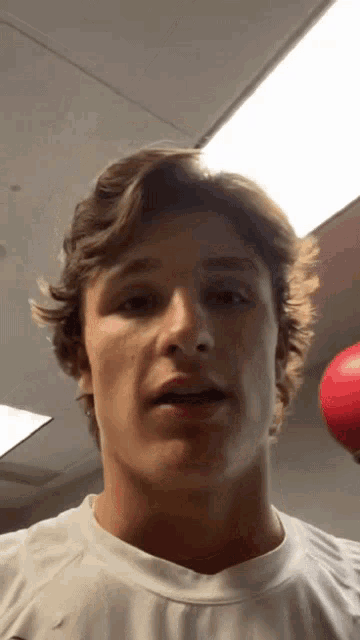 a close up of a man 's face with a red boxing glove in the background