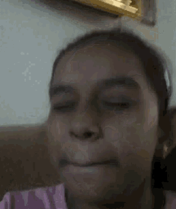 a young girl is making a funny face with her eyes closed .