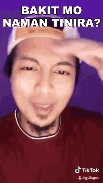 a man wearing a hat and a red shirt is making a funny face and says bakit mo naman tinira ?