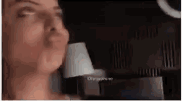 a woman is making a funny face in front of a mirror in a dark room .