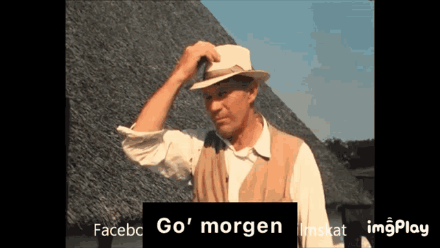 a man wearing a hat is standing in front of a thatched roof and a sign that says go ' morgen