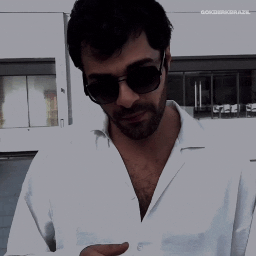 a man wearing sunglasses and a white shirt has the word gokberkerazl above his head