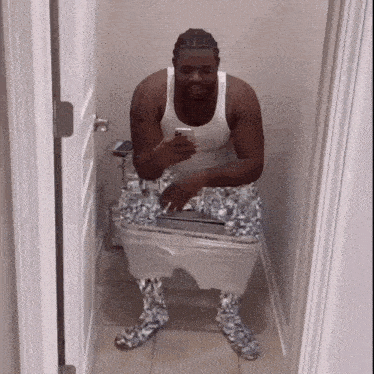 a man sitting on a toilet with his pants down and calvin klein socks on