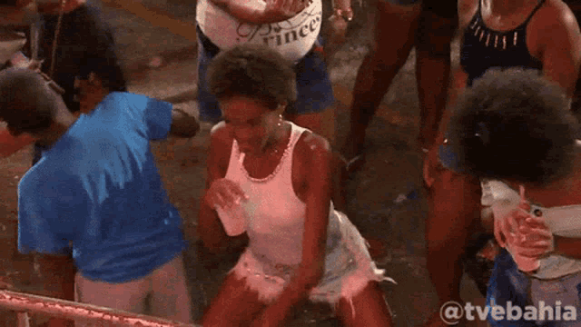 a woman drinking through a straw in a crowd with the hashtag @tvebahia on the bottom