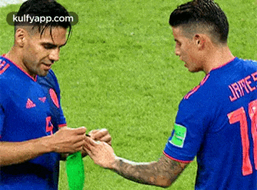 two soccer players are shaking hands on the field during a game .