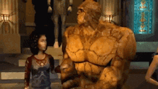 a woman is standing next to a statue of the thing in a video game .