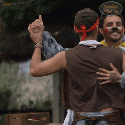 a man in a pirate costume is hugging another man in front of a sign that says paradiso del paradiso