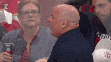 a man in a suit and a woman in glasses are watching a game with the word usa on their hat