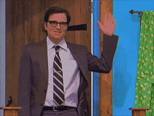 a man in a suit and tie waving his hand