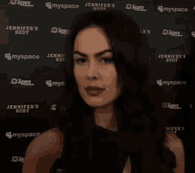 a woman is standing in front of a wall with jennifer 's body written on it