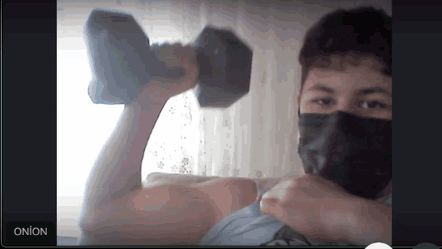 a man wearing a face mask is lifting a dumbbell in front of a screen that says onion on it