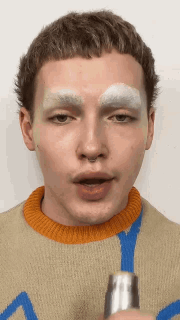 a close up of a man 's face with white eyebrows and a sweater on .