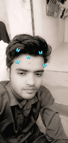 a black and white photo of a young man with butterflies on his forehead
