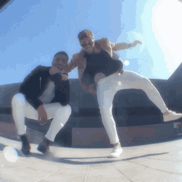 two men are posing for a picture and one of them is wearing white pants