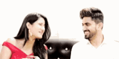 a man and a woman are sitting next to each other on a couch and smiling .
