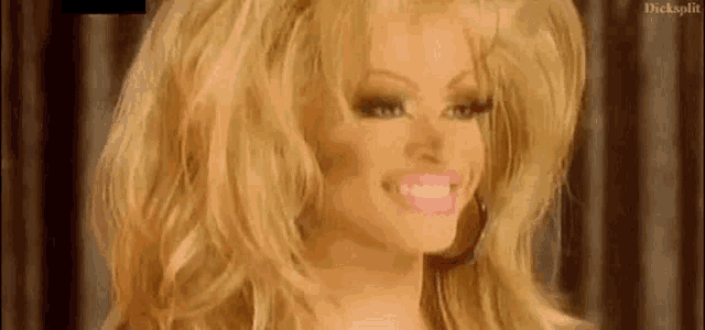 a woman with blonde hair and pink lips is smiling and making a face .