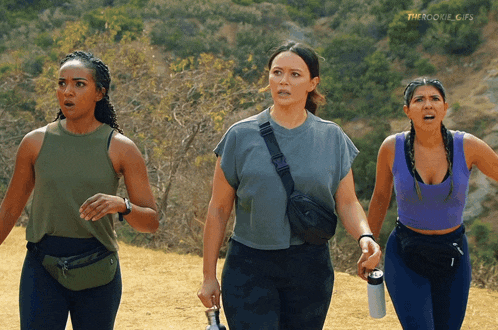 three women are walking down a dirt path with the words " therookie gifs " in the corner