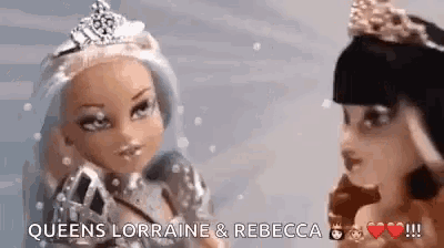 two dolls with tiaras on their heads are standing next to each other in the snow .