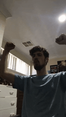 a man in a blue shirt flexes his muscles in front of a sign that says 100