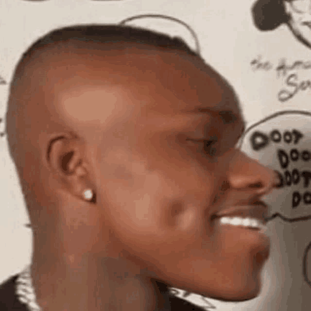 a close up of a man 's face with a shaved head and earrings smiling .