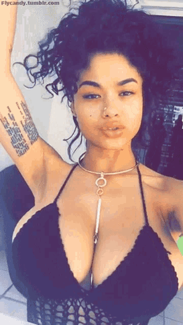 a woman with a tattoo on her arm is wearing a black top and a necklace