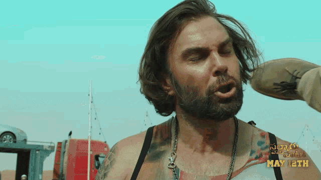 a man with a beard is standing in the desert and the date may 12th is on the bottom