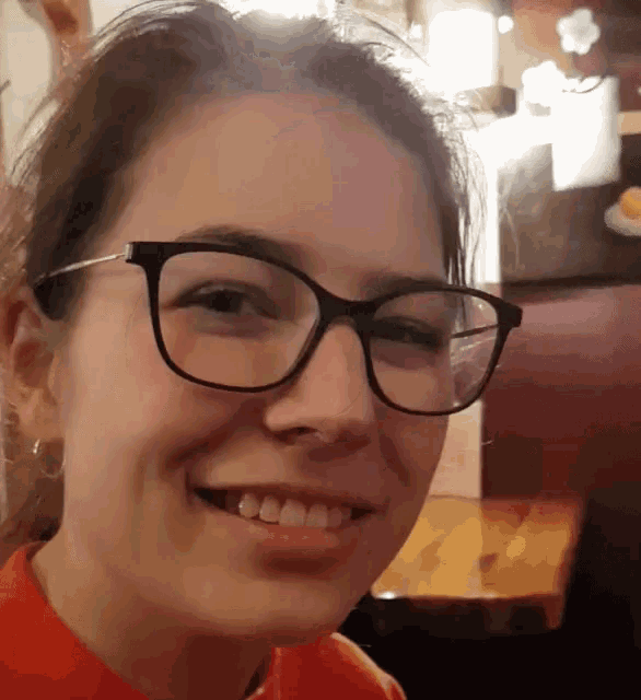 a woman wearing glasses and a red shirt smiles for the camera