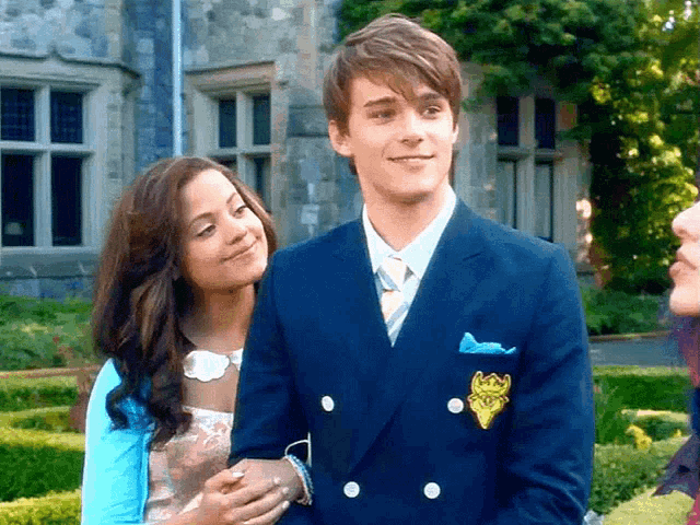 a man and a woman are standing next to each other with the man wearing a blue suit and tie