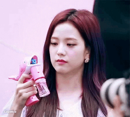 a close up of a woman holding a pink bubble gun