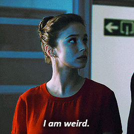 a woman in a red shirt says i am weird in front of a green exit sign