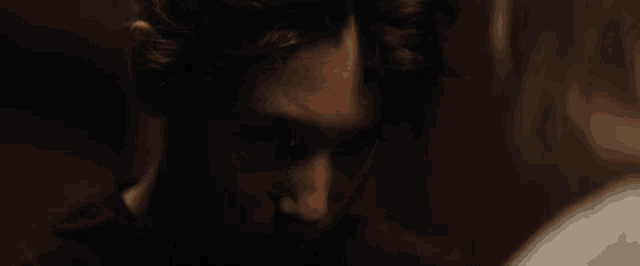 a close up of a woman 's face in a dark room looking at the camera .