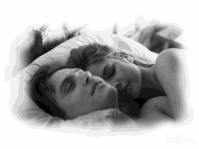 a black and white photo of a man and woman sleeping on a bed
