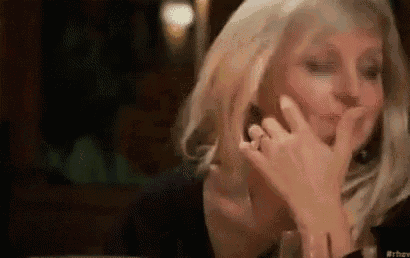 a woman is sitting at a table with her hand on her face .
