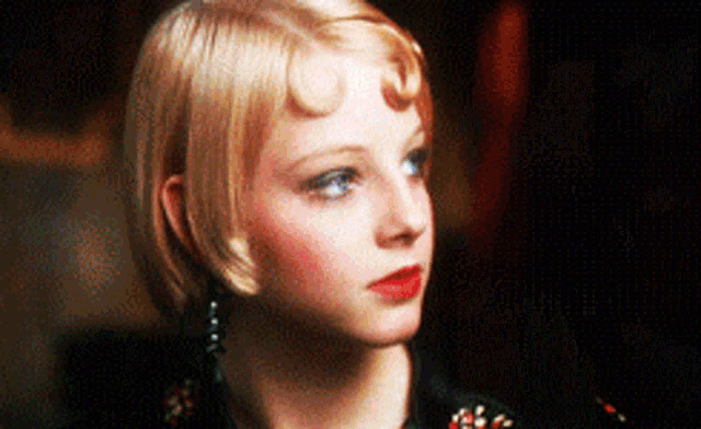 a woman with blonde hair and red lipstick is wearing earrings