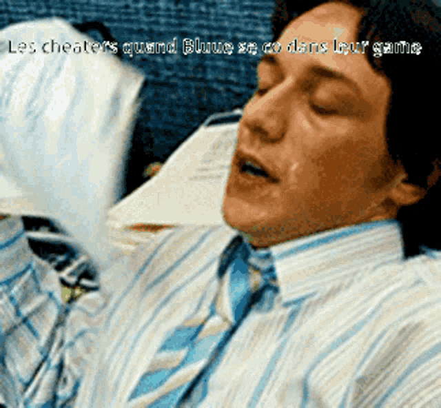 a man in a blue and white striped shirt and tie is laying down