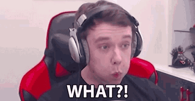 a man wearing headphones is sitting in a gaming chair and making a funny face .