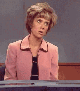 a woman in a pink jacket is sitting at a desk with her mouth open