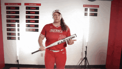 a woman in a red semo jersey is holding a easton bat