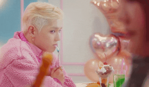 a man in a pink jacket is eating a dessert with a fork
