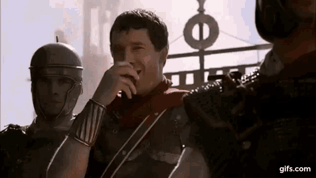 a man in a roman soldier costume is laughing while standing next to another man .