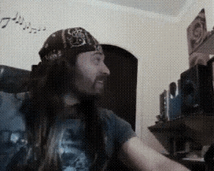 a man with long hair and a bandana is sitting in a room .