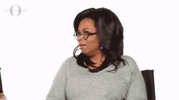 a woman wearing glasses and a grey sweater with the letter o on the bottom right