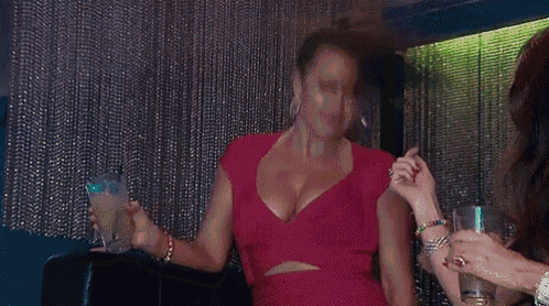 a woman in a red dress is holding a drink in her hand and dancing .