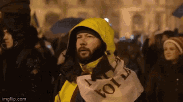 a man wearing a yellow jacket holds a sign that says " voi "