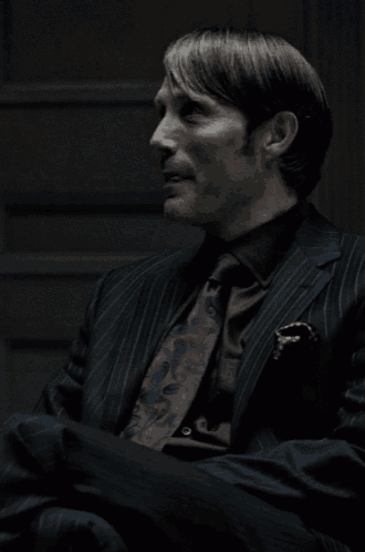 a man in a suit and tie looks to his left