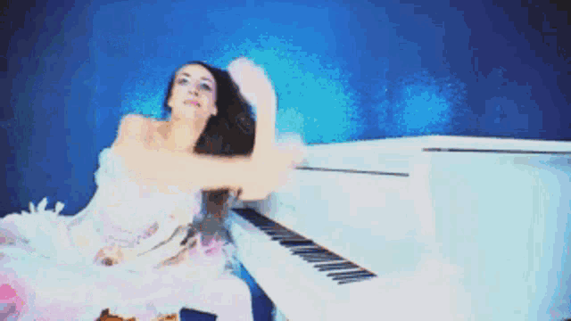 a woman in a white dress sits on a white piano
