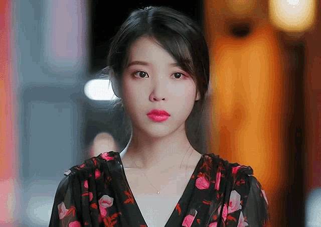 a close up of a woman wearing a black and pink floral dress