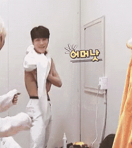a man is taking off his shirt in a room while another man looks on .